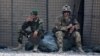 FILE - In this Aug. 5, 2015 photo, an Afghan National Army soldier, left, smokes as a U.S. Army soldier from Charlie Company, 2-14 Infantry Regiment, 2nd Brigade, 10th Mountain Division sits next to him in Camp Khogyani in Nangarhar province, east of Kabul, Afghanistan.