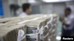 FILE - Stacks of Myanmar kyat are seen at a bank in Yangon, Myanmar Oct. 19, 2015. The National Unity Government in Myanmar introduced its own digital currency in 2022 to bypass banks controlled by the junta.