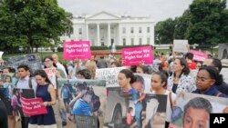 People hold up signs and photographs during a demonstration opposed to the White House policy that separated more than 2,300 children from their parents over the past several weeks in front of the White House in Washington, June 21, 2018.