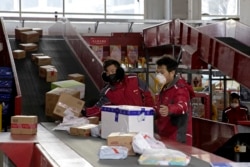 Pekerja pengiriman untuk raksasa e-commerce China JD.com memilah parsel di pusat distribusi di Beijing, China, 18 Februari 2020. (AP)