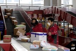 Pekerja pengiriman untuk raksasa e-commerce China JD.com memilah parsel di pusat distribusi di Beijing, China, 18 Februari 2020. (AP)