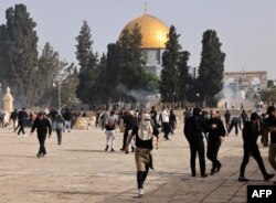Palestinians run for cover from tear gas fired by Israeli security forces at Jerusalem's Al-Aqsa mosque area on May 10, 2021