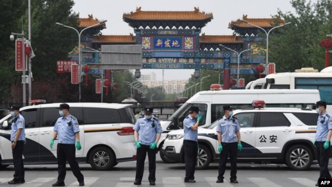 中国警察在被关闭的北京新发地农产品批发市场的入口处站岗。（2020年6月13日）