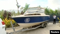 An officer takes pictures of a boat, which Australian police have seized in Cairns, Queensland, Australia in this still image taken from video, May 11, 2016.