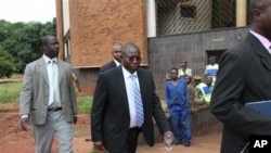 Elton Mangoma, center, Zimbabwe's Minster of Energy and Power Development outside the magistrates courts, accompanied by two unidentified police detectives in Harare, March, 11, 2011.