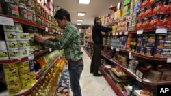 Mohammad Kouhi, left, and Hassan Akbarzadeh, work, in a supermarket in Tehran, Iran, January 23, 2013.