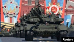 FILE - A Russian serviceman aboard a tank salutes during the Victory Day parade in Moscow's Red Square May 9, 2014.