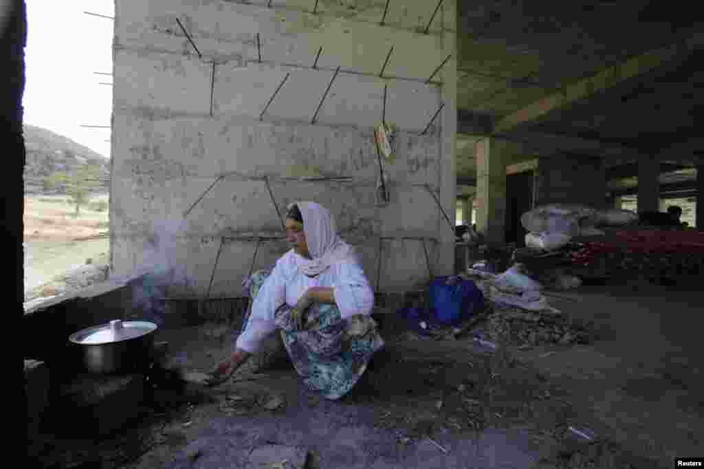 A woman from the minority religious Yazidi sect who fled from the town of Sinjar, cooks in an abandoned building, Dohuk, Aug. 14, 2014.