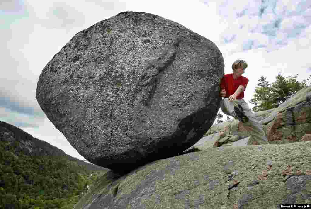 Doris Morgan, of Tampa, Florida, tires to dislodge the Bubble Rock near the summit of South Bubble Mountain in Acadia National Park near Bar Harbor, Maine.