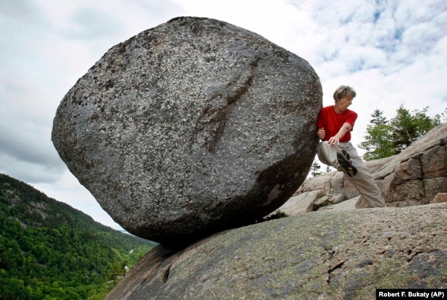 Doris Morgan, of Tampa, Fla., playfully attempts to dislodge the Bubble Rock near the summit of South Bubble Mountain, Friday, June 4, 2010, in Acadia National Park near Bar Harbor, Maine.