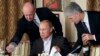 FILE - In this Nov. 11, 2011, photo, businessman Yevgeny Prigozhin, left, serves food to Russian Prime Minister Vladimir Putin, center, during dinner at Prigozhin's restaurant outside Moscow, Russia. 