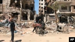 Gente observa daños a edificios en la ciudad de Douma, cerca de Damasco, Siria, sitio de presunto ataque con armas químicas.
in the town of Douma, the site of a suspected chemical weapons attack, near Damascus, Syria, April 16, 2018.