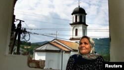 Fata Orlovic, 60, stands in front of the window in her devastated home in the village of Konjevic Polje in eastern Bosnia September 8, 2002