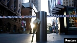 FILE - A bouquet is pictured under police tape near the cordoned-off scene of a hostage taking at Martin Place after it ended early Dec. 16, 2014. 