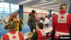 Evacuees arrive to seek shelter with Red Cross volunteers at the George Brown convention center after flood waters of Hurricane Harvey forced them to leave their homes in Houston, Aug. 27, 2017.