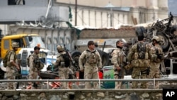 FILE - In this April 19, 2016 file photo, Afghan security forces inspect the site of a Taliban-claimed deadly suicide attack in Kabul, Afghanistan. Blamed this attack in Kabul, the Haqqani network, declared a terrorist organization by the United States, is on the ascendency within the Taliban, uniting disgruntled warriors and bringing military cohesiveness to the battlefield raising fears that the summer fighting season will be ferocious. 