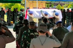 Petugas mengusung peti jenazah salah satu perwira yang gugur di Mimika, 28 April 2021, dalam baku tembak antara polisi dan pemberontak separatis di wilayah Papua yang bergolak. (Foto oleh Saldi HERMANTO / AFP)