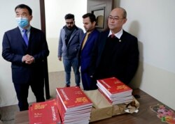 Chinese lecturer, Zhiwei Hu, left, teachers and officials of the Chinese Language Department stand in front of Chinese language books intended for students in Salahaddin University in Irbil, Iraq, Jan. 19, 2021.