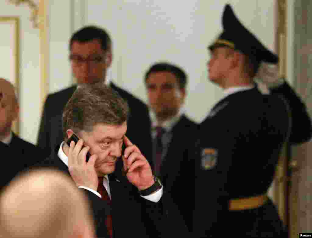 Ukraine's President Petro Poroshenko (front) speaks on the phone as he attends a peace summit to resolve the Ukrainian crisis in Minsk, February 12, 2015.