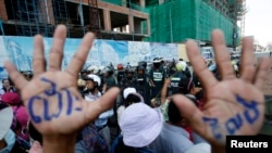 A man, with his hands painted with words that translate to "Release", demonstrate to demand the release of five opposition members of parliament, as police officers block a street near the Phnom Penh Municipal Court in central Phnom Penh, Cambodia, July 1