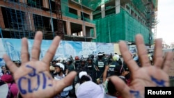 A man, with his hands painted with words that translate to "Release", demonstrate to demand the release of five opposition members of parliament, as police officers block a street near the Phnom Penh Municipal Court in central Phnom Penh, Cambodia, July 1