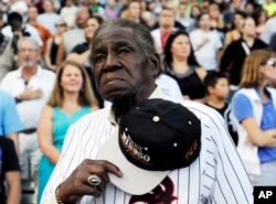 FILE - Former Negro Leaguer and Chicago White Sox player Minnie Minoso stands during the national anthem before a baseball game between the Chicago White Sox and the Texas Rangers, in Chicago, Aug. 24, 2013.