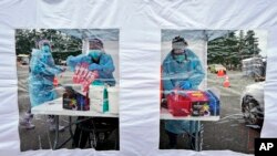 FILE - Workers at a drive-up COVID-19 testing clinic stand in a tent as they prepare PCR coronavirus tests, Jan. 4, 2022, in Puyallup, Wash., south of Seattle.