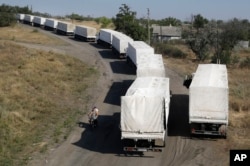 Trucks from Russian aid convoy to Ukraine stand in line as they return to Russia on the border post at Izvaryne, eastern Ukraine, Aug. 23, 2014.