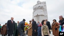 Menteri Keamanan Dalam Negeri AS, Jeh Johnson (kiri) meletakkan karangan bunga di depan patung Dr. Martin Luther King, Jr. hari Senin (19/1).