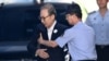 Former South Korean president Lee Myung-bak, left, is helped by a prison official as he arrives at a court to attend his trial in Seoul, Sept. 6, 2018.