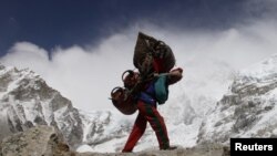 Un nepalés camina con el fondo del Himalaya. Al menos nueve personas murieron en una avalancha cerca de la cima del Monte Manaslu, en Nepal.