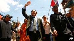 FILE - Cambodia's main opposition Cambodia National Rescue Party Vice President Kem Sokha, center, waves during a protest rally in Phnom Penh, Cambodia, May 20, 2013.