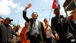 Cambodia's main opposition Cambodia National Rescue Party Vice President Kem Sokha, center, waves during a protest rally in Phnom Penh, Cambodia, May 20, 2013. 