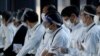 Petugas yang mengenakan pelindung wajah dan masker menunggu penumpang yang membutuhkan kursi roda di pintu kedatangan Bandara Internasional Narita, timur Tokyo, Jepang, 30 November 2021. (Foto: REUTERS/Kim Kyung-Hoon)