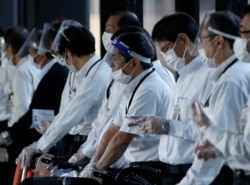 Staffs wearing face shields and masks wait for passengers who need wheelchairs at an arrival gate of Narita international airport on the first day of closed borders to prevent the spread of the new Omicron variant in Narita, east of Tokyo, Japan, Nov. 30,