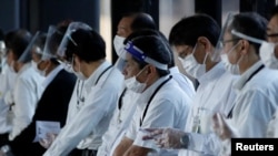 Staffs wearing face shields and masks wait for passengers who need wheelchairs at an arrival gate of Narita international airport on the first day of closed borders to prevent the spread of the new Omicron variant in Narita, east of Tokyo, Japan, Nov. 30, 2021.