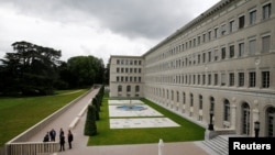 FILE - People talk outside the headquarters of the World Trade Organization (WTO) in Geneva, Switzerland, June 3, 2016. 