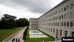 FILE - People talk outside the headquarters of the World Trade Organization (WTO) in Geneva, Switzerland, June 3, 2016. 