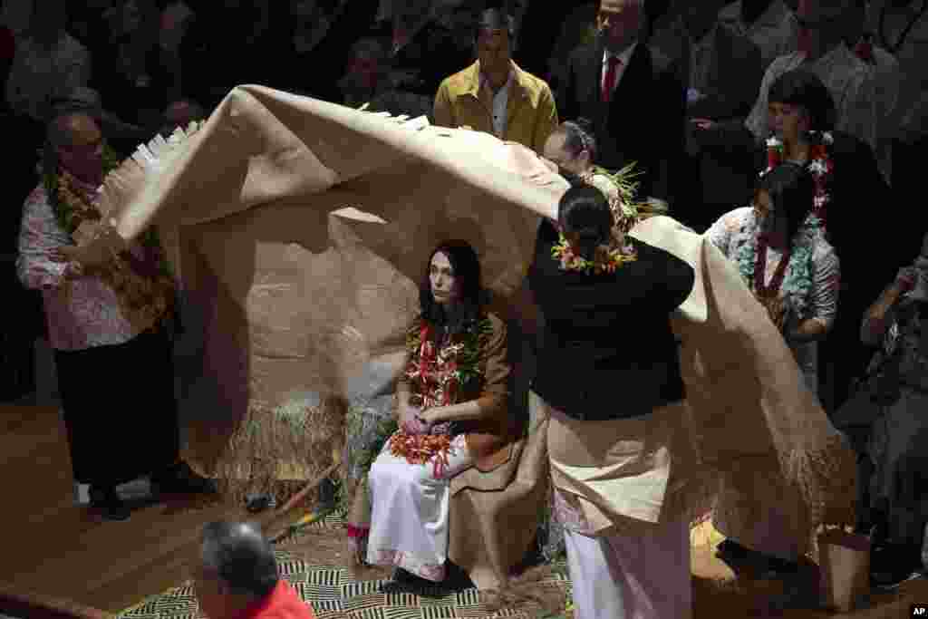 New Zealand Prime Minister Jacinda Ardern, center, is covered during a ceremony in Auckland, to formally apologize for a racially charged part of the nation&#39;s history known as the Dawn Raids.