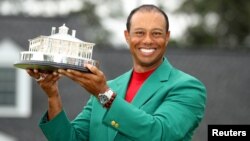 FILE - Tiger Woods wears his green jacket and holds his trophy after winning the 2019 Masters in Augusta, Georgia, April 14, 2019.