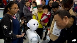 FILE - Visitors crowd around Pepper, a companion robot, during the World Robot Conference in Beijing. China, Oct. 21, 2016. 