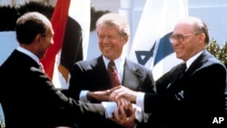 FILE - In this March 26, 1979 file photo, Egyptian President Anwar Sadat, left, U.S. President Jimmy Carter, center, and Israeli Prime Minister Menachem Begin clasp hands on the North Lawn of the White House as they completed signing of the peace treaty b