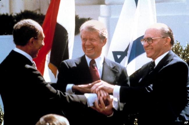 FILE - In this March 26, 1979 file photo, Egyptian President Anwar Sadat, left, U.S. President Jimmy Carter, center, and Israeli Prime Minister Menachem Begin clasp hands on the lawn of the White House as they completed signing of the peace treaty. (AP Photo/Bob Daugherty, File)