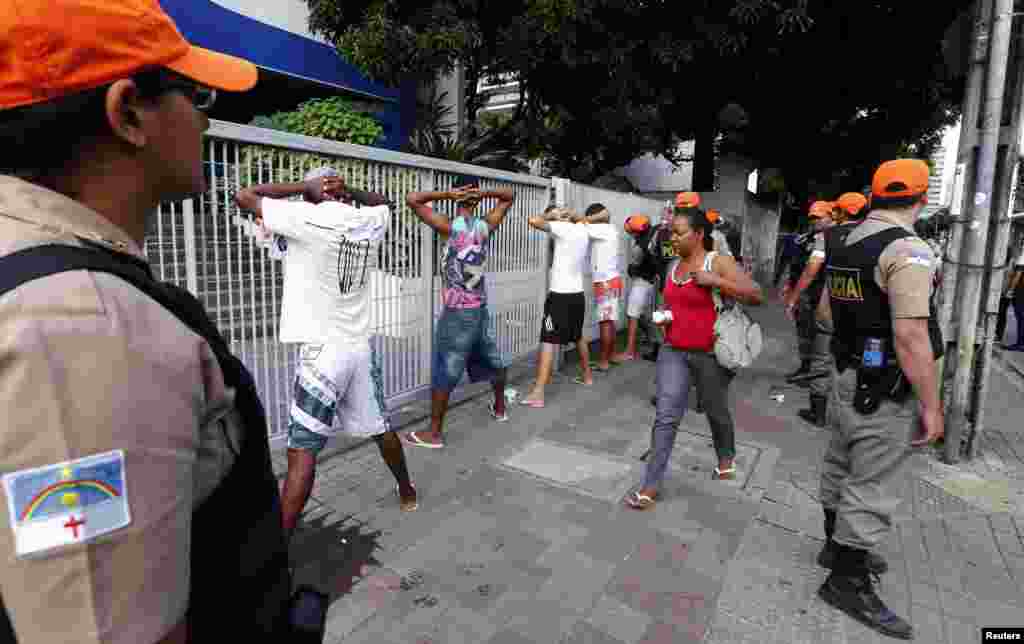 A woman walks past demonstrators detained for vandalism, as policemen stand guard, Recife City, Brazil, June 20, 2013.