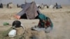 资料照片：一名为躲避战火而背井离乡的阿富汗妇女在马扎里沙里夫城边的临时帐篷营地内的干硬土地上烧柴煮茶。(2021年7月8日)