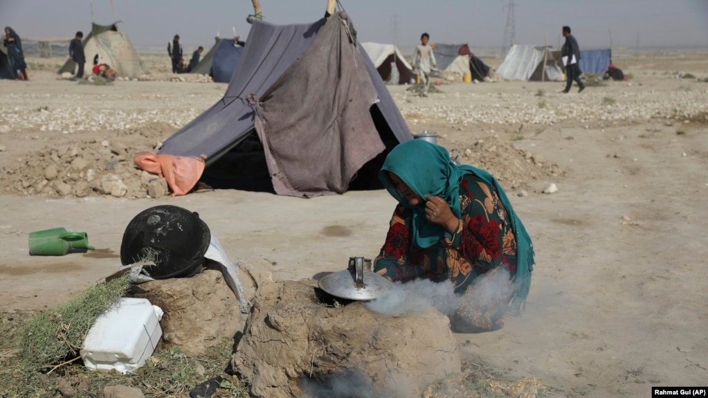 资料照片：一名为躲避战火而背井离乡的阿富汗妇女在马扎里沙里夫城边的临时帐篷营地内的干硬土地上烧柴煮茶。(2021年7月8日)(photo:VOA)