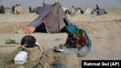 一名為躲避戰火而背井離鄉的阿富汗婦女在馬扎里沙裡夫城邊的臨時帳篷營地內的干硬土地上燒柴煮茶。(2021年7月8日)