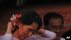 Myanmar's pro democracy leader Aung San Suu Kyi, places flowers from a supporter in her hair after her release from house arrest in Rangoon, Burma, 13 Nov 2010