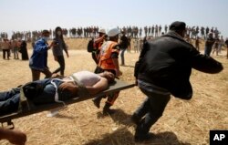 Palestinian protesters and civil defense evacuate a wounded youth during clashes with Israeli troops along Gaza's border with Israel, east of Khan Younis, April 6, 2018.