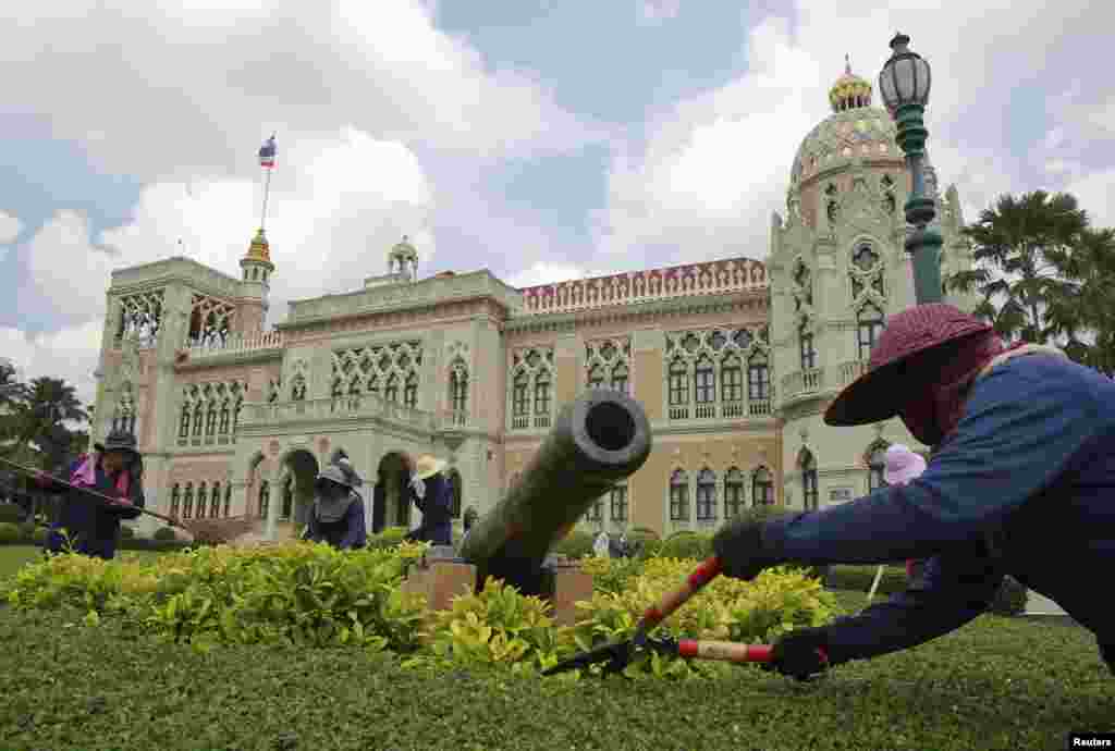 Workers trim bushes in preparation for the new cabinet at the Government House in Bangkok, Aug. 25, 2014.